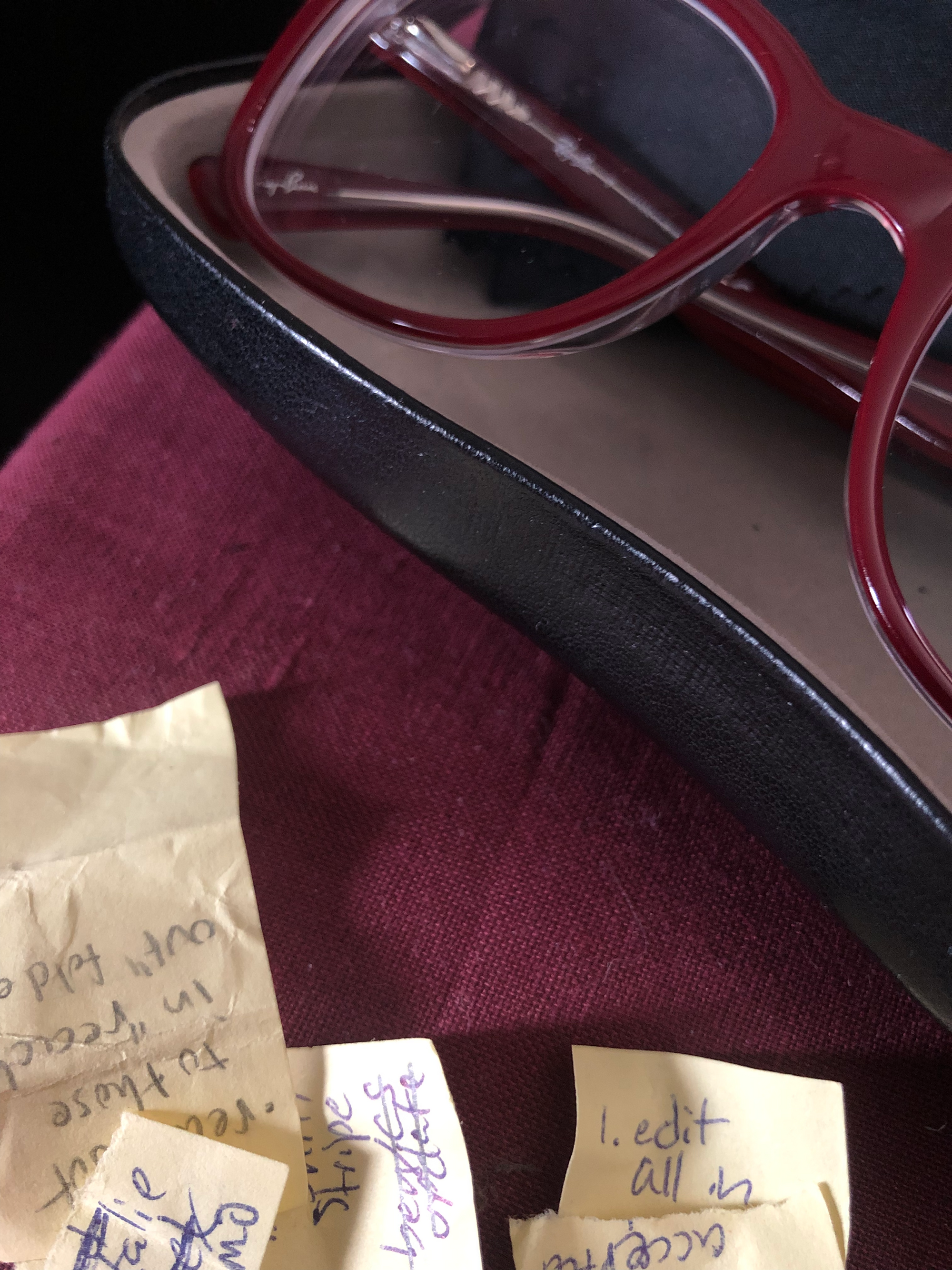 close-up photo of an open black glasses case with red Ray-Ban eyeglasses sitting inside, next to a bunch of crumpled Post-Its with writing on them, a few words legible: "to those in... out fold", "Stripe", "1. edit all in". taken at the robledo art, strike! headquarters, february 2023.