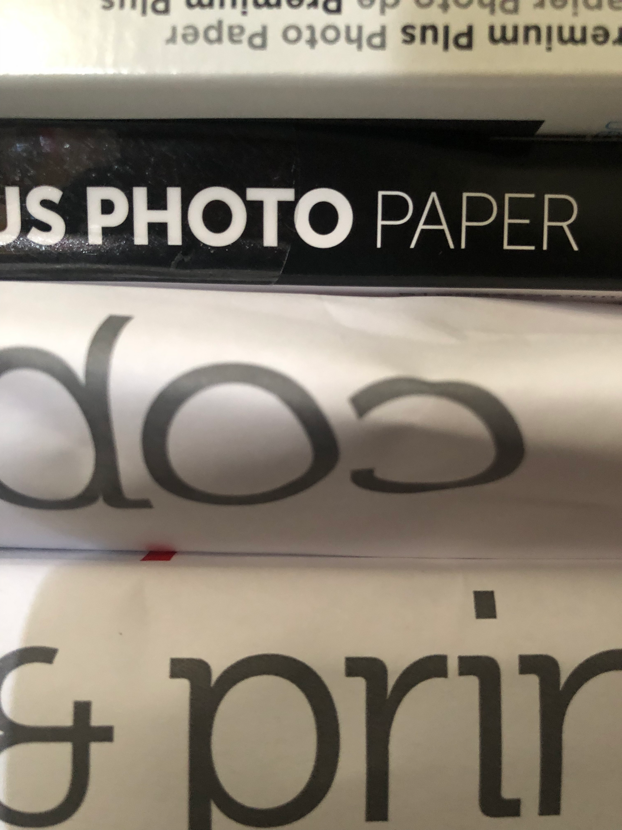 close-up photo of stacks of paper wrapped in covering that reads, from top to bottom: "Premium Plus Photo Paper", "PHOTO PAPER", "cop", "& print". taken at the robledo art, strike! headquarters, february 2023.